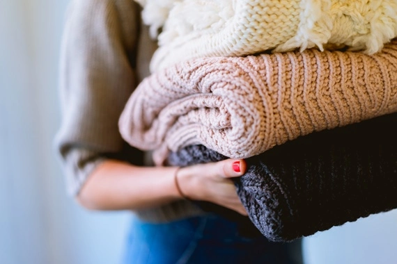 Kobieta trzymająca swetry po praniu